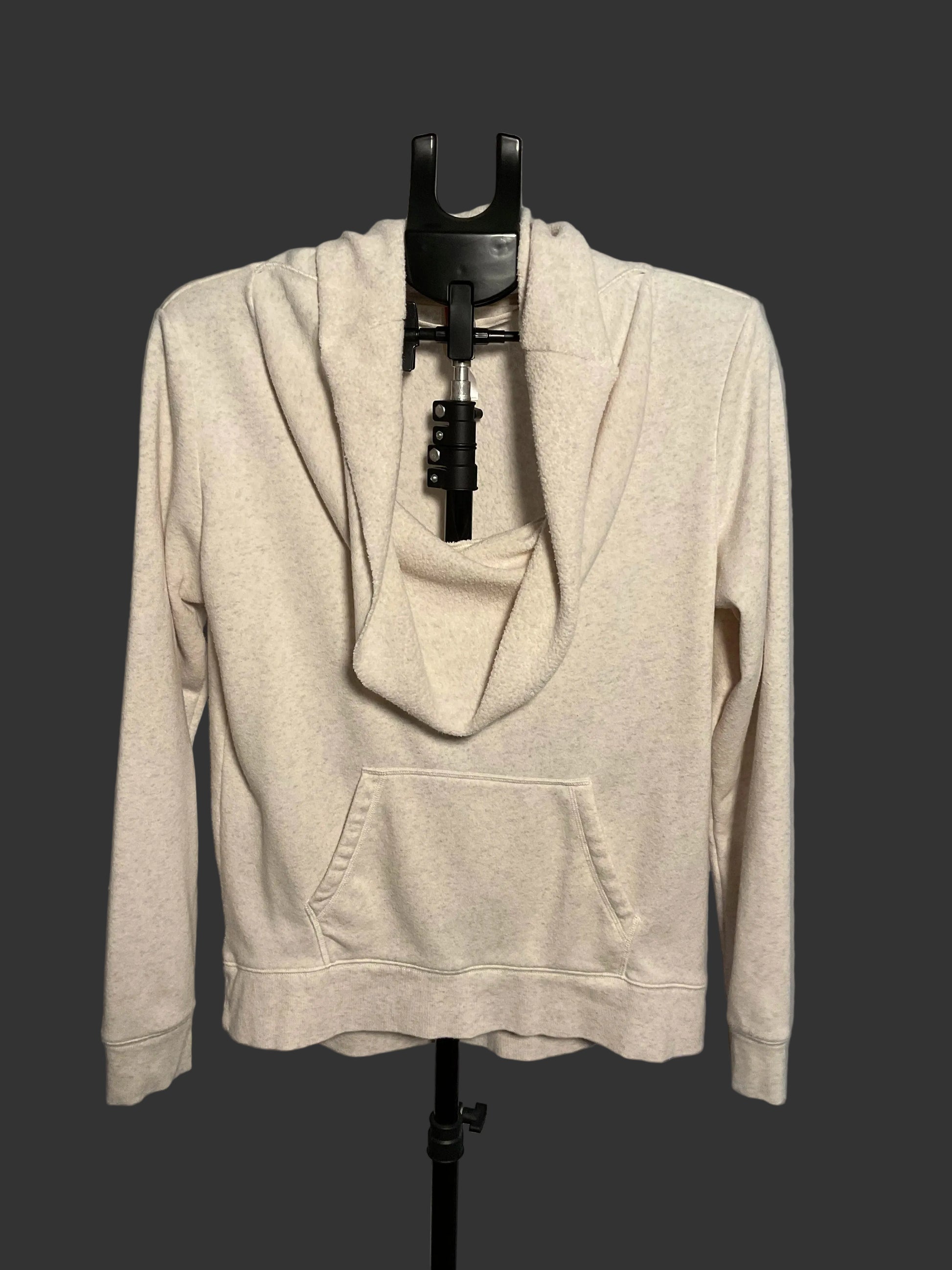 A light beige heathered cowl neck pullover hoodie with a front kangaroo pocket, displayed on a black dress form stand against a gray background.