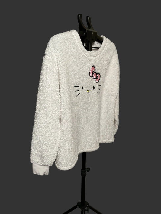 A white sherpa fleece long-sleeve sweatshirt featuring a Hello Kitty face and bow graphic on the front, displayed on a black clothing hanger stand against a gray studio backdrop.