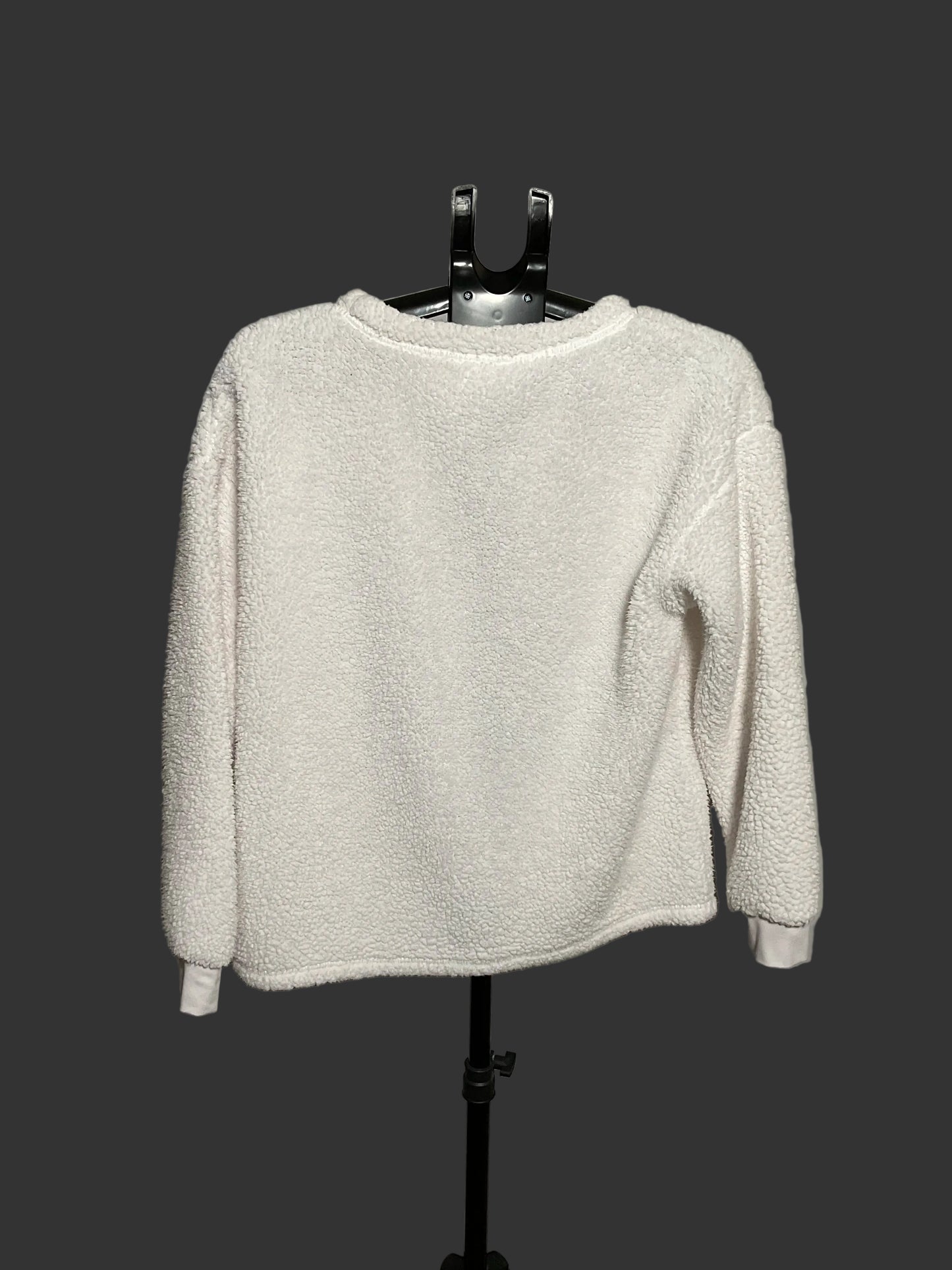 A white textured fleece long-sleeve top displayed on a black hanger stand against a circular gray backdrop.