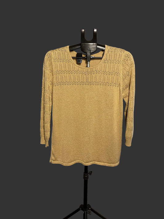 A mustard yellow knit sweater with a textured geometric pattern across the chest and shoulders, displayed on a black hanger stand against a white circular studio backdrop.