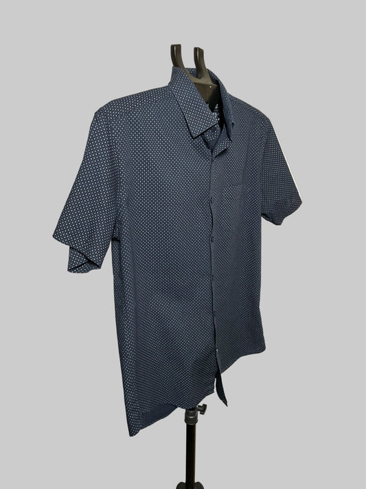 A short-sleeve button-up shirt in navy blue with a small white geometric pattern, displayed on a black dress form mannequin against a white studio background.