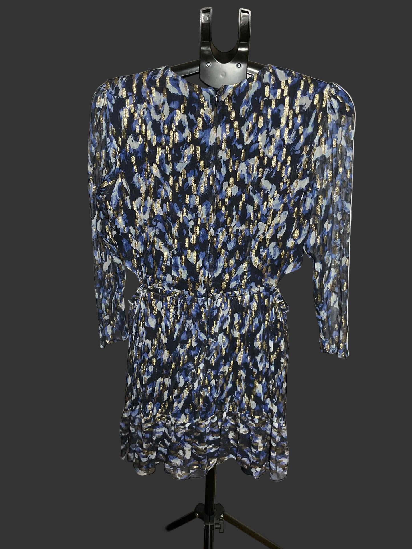 A long-sleeve mini dress with a blue, black, and beige abstract pattern, displayed on a black hanger stand against a white studio backdrop.