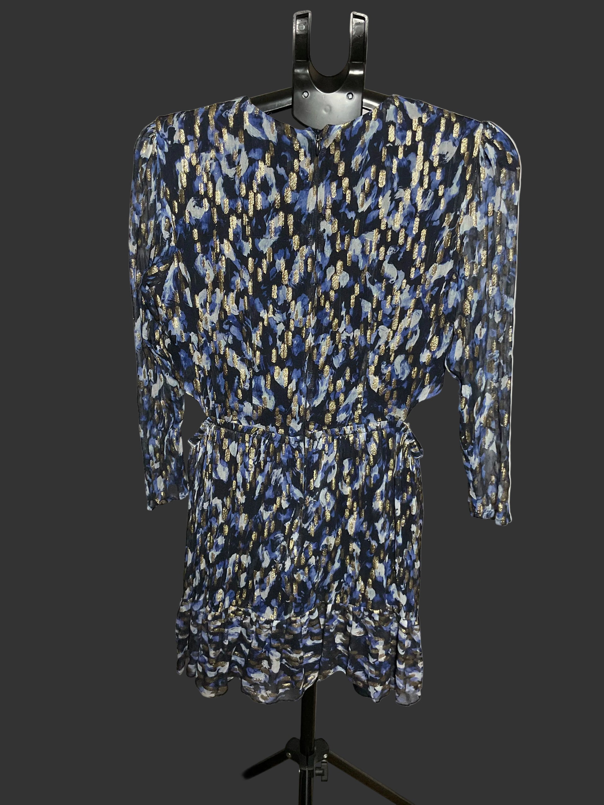 A long-sleeve mini dress with a blue, black, and beige abstract pattern, displayed on a black hanger stand against a white studio backdrop.