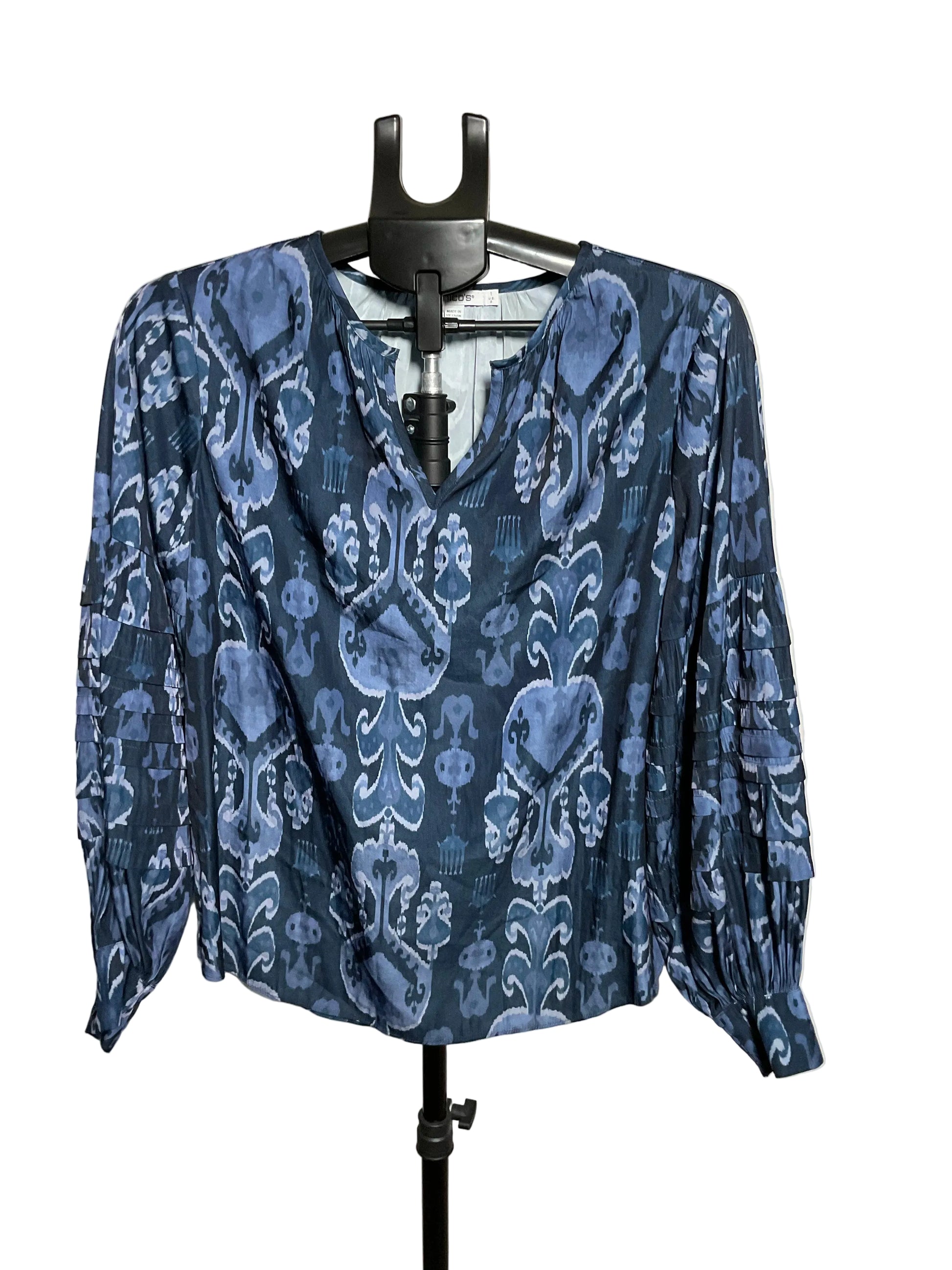 A blue and navy patterned blouse with long sleeves and a V-neckline, displayed on a black hanger stand against a plain light background.