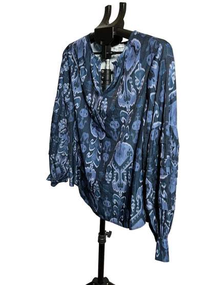A blue and navy patterned long-sleeve blouse displayed on a black hanger stand against a plain off-white wall.