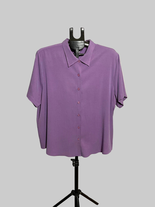 A purple short-sleeve button-up shirt displayed on a black dress form mannequin stand against a white circular backdrop.