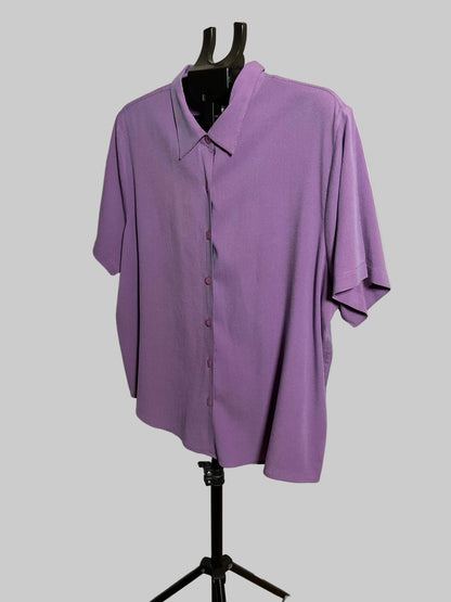 A lavender purple short-sleeve button-up shirt displayed on a black dress form mannequin stand against a white studio backdrop.