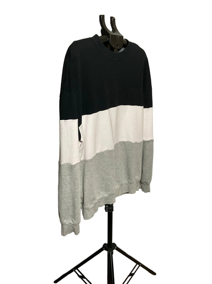A long-sleeve crewneck sweatshirt with a color-blocked design in black, off-white, and light gray, displayed on a black clothing hanger stand against a white studio backdrop.
