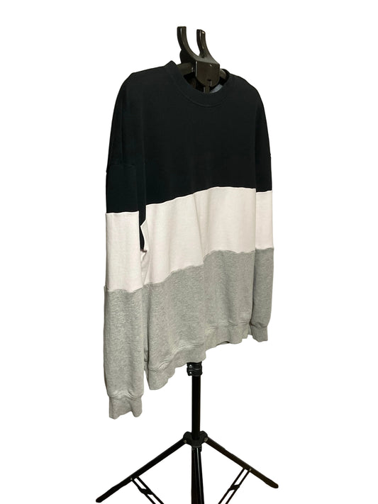 A long-sleeve crewneck sweatshirt with a color-blocked design in black, off-white, and light gray, displayed on a black clothing hanger stand against a white studio backdrop.