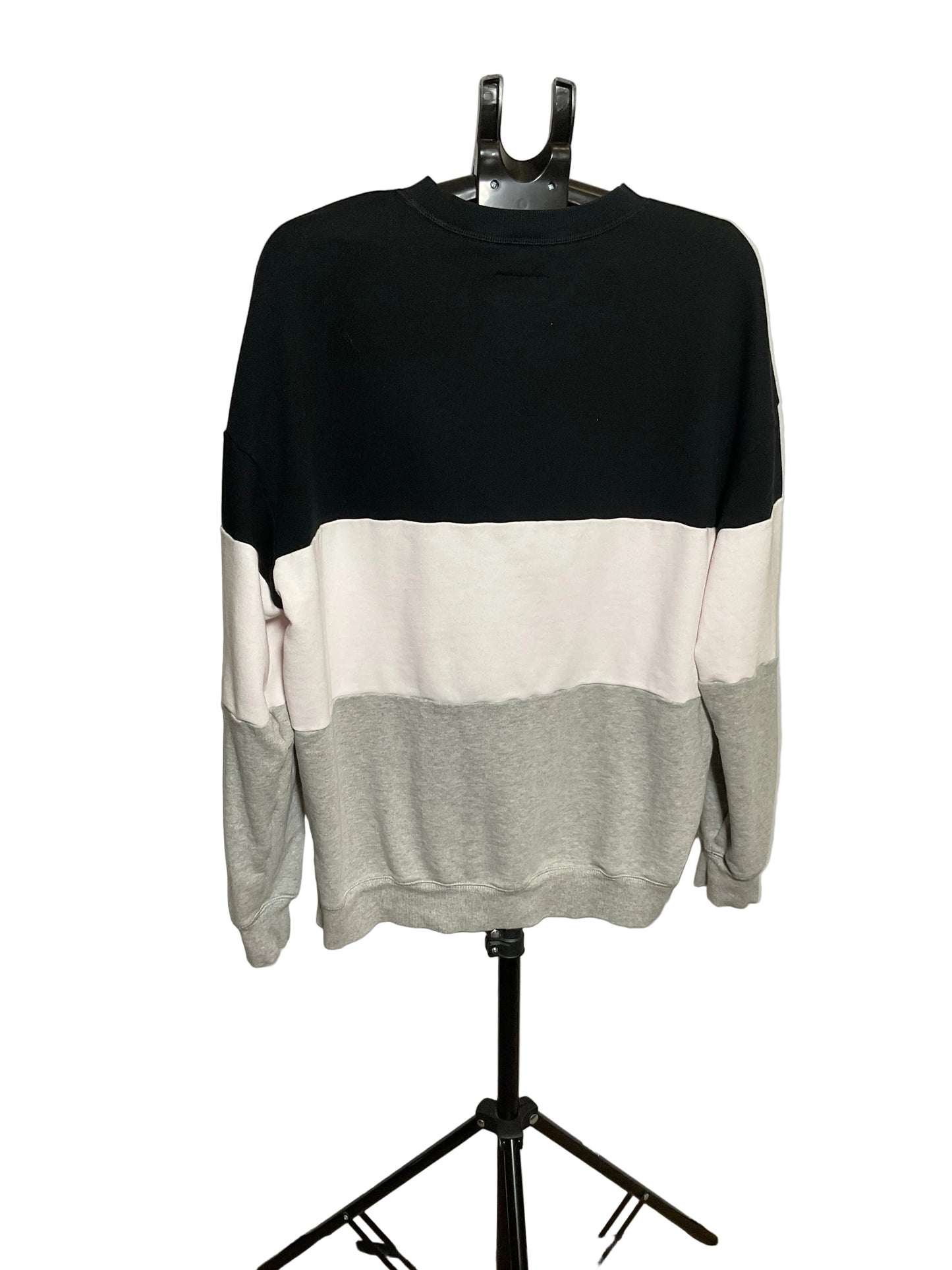 A color-block crewneck sweatshirt displayed on a black hanger stand against a white studio backdrop. The sweatshirt features three horizontal color blocks: black on top, off-white in the middle, and light gray on the bottom and sleeves.