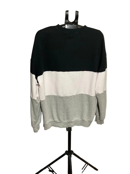A color-block crewneck sweatshirt displayed on a black hanger stand against a white studio backdrop. The sweatshirt features three horizontal color blocks: black on top, off-white in the middle, and light gray on the bottom and sleeves.