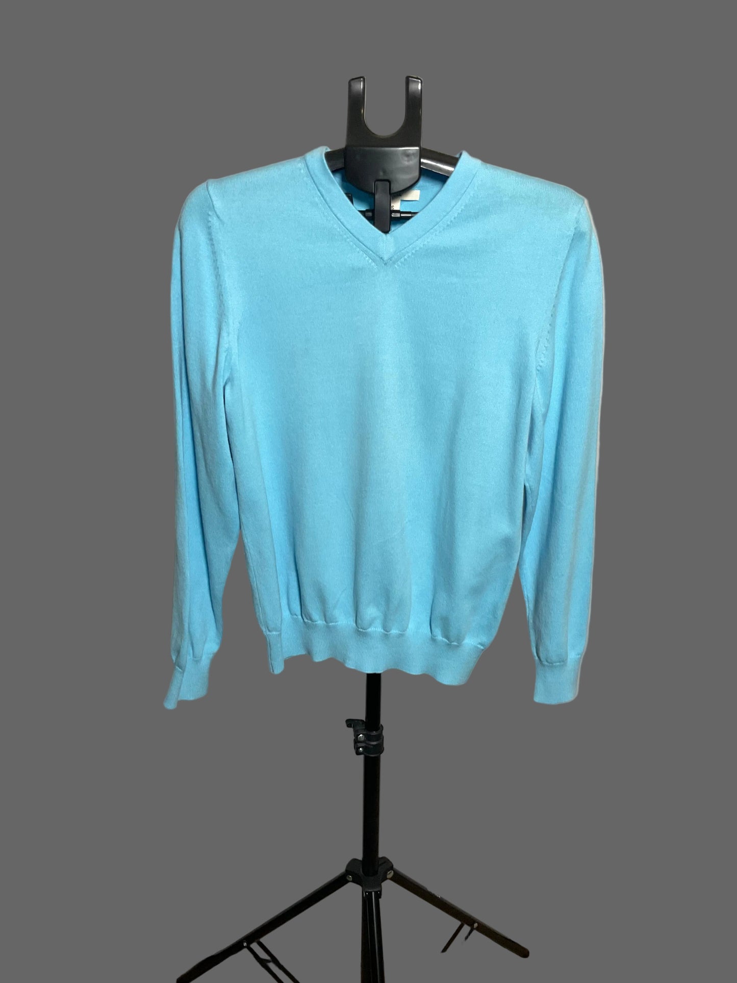 A light blue long-sleeve V-neck sweater displayed on a black hanger stand against a white circular backdrop.