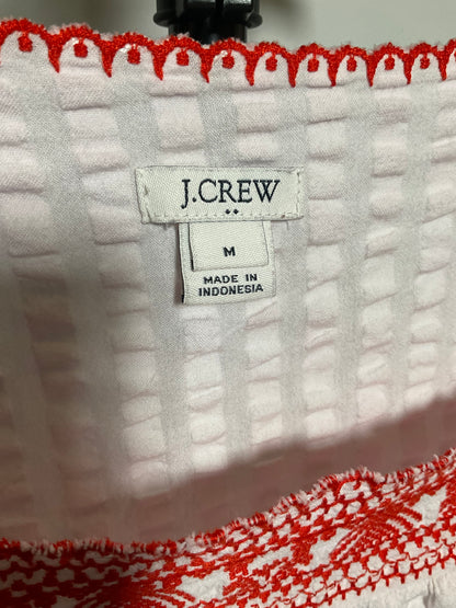 Close-up of a white textured fabric item with red scalloped trim and a visible J.CREW size label reading M.