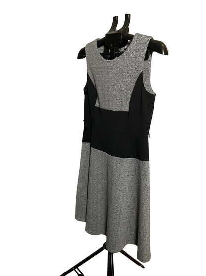 A sleeveless color-block knit dress displayed on a black dress form mannequin. The dress features a heather gray and black color-blocked design, photographed against a white circular studio backdrop.