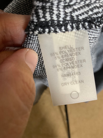 A close-up of a hand holding a garment label attached to black-and-white patterned fabric, with the text showing material composition: 95% polyester, 5% spandex.