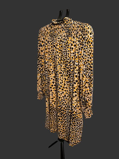 A long-sleeve smocked blouse with an all-over leopard print pattern in yellow, black, and brown, displayed on a black hanger stand against a white circular studio backdrop.