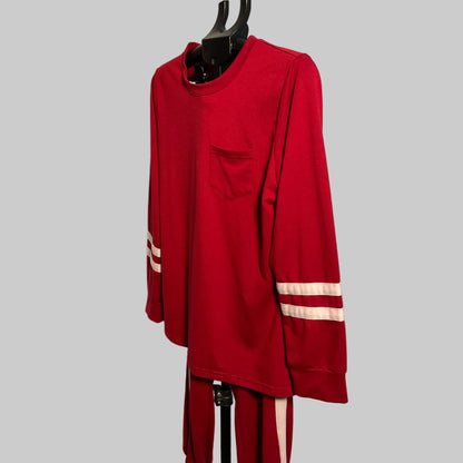 A red long-sleeve crewneck shirt with a chest pocket and white stripes on the sleeves, hanging on a black hanger against a plain light wall.