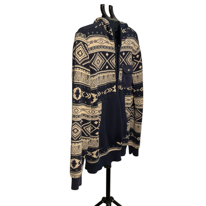 A navy blue and cream geometric patterned zip-up hoodie with a front pocket, hanging on a black hanger stand against a white circular backdrop.