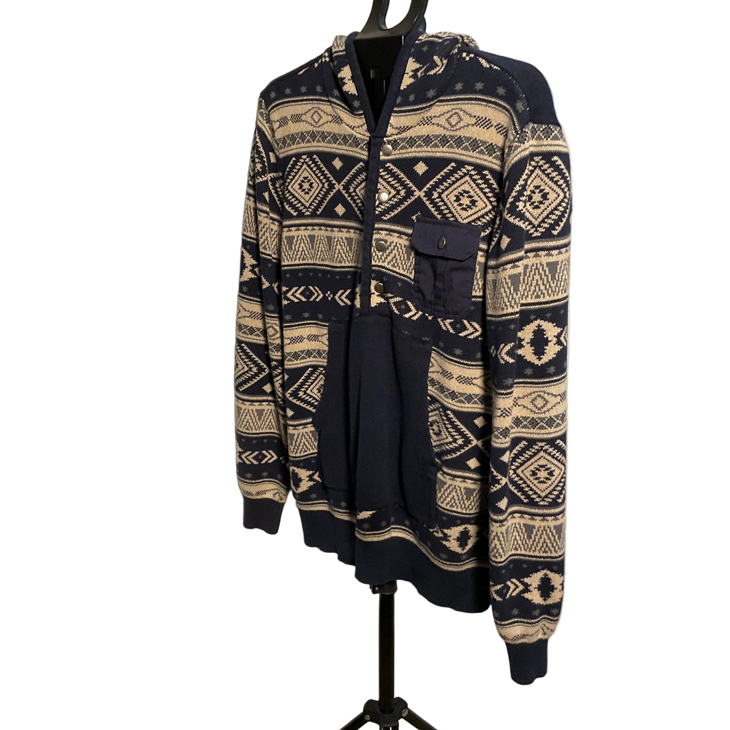 A navy blue and beige patterned zip-up hoodie with a hood and front pockets, displayed on a black hanger stand against a white circular backdrop.
