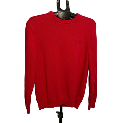 A bright red crewneck knit sweater with a small embroidered logo on the left chest, displayed on a black hanger against a plain light beige wall.