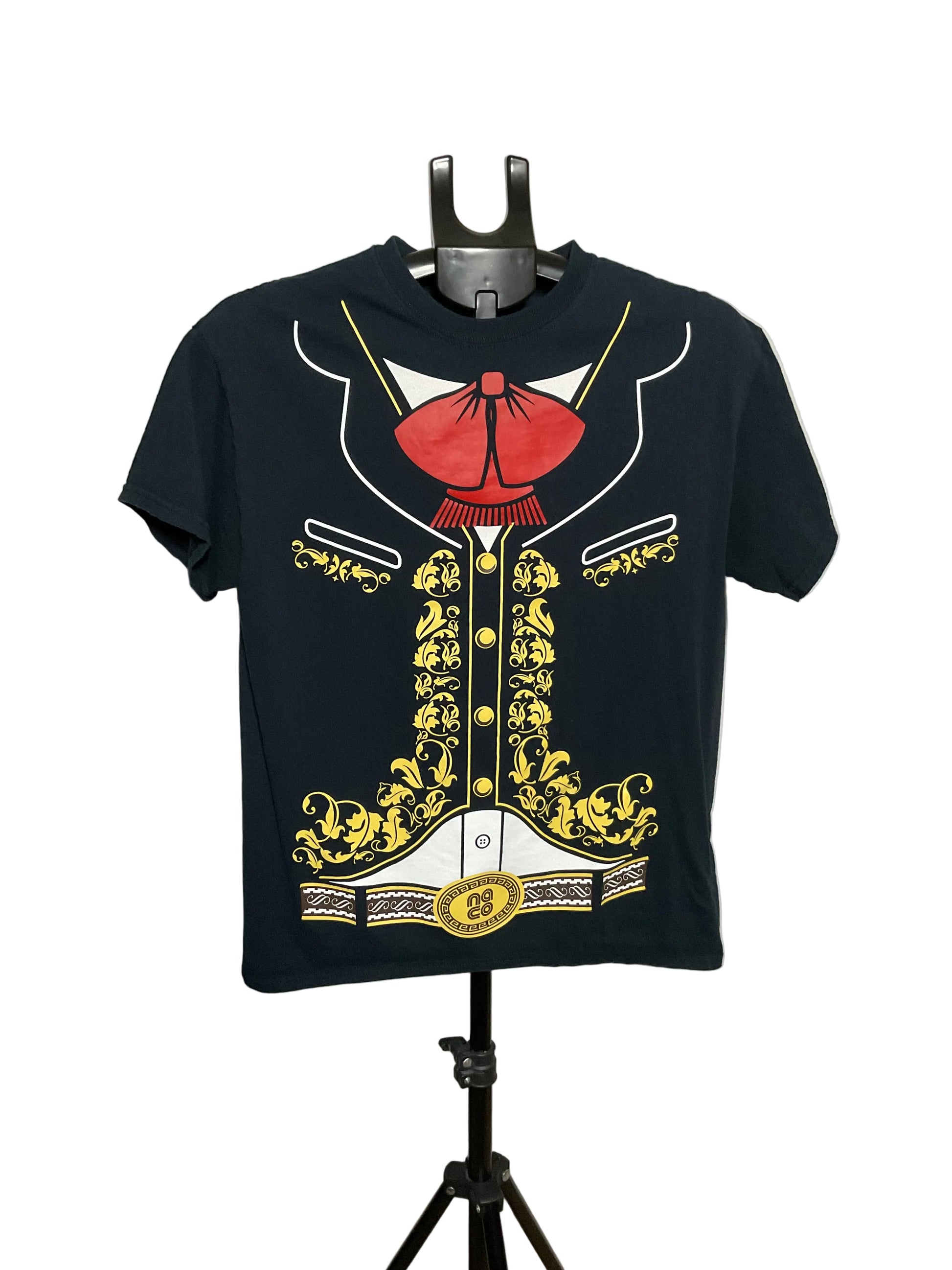 A black short-sleeve t-shirt displayed on a black hanger stand against a plain light gray wall. The shirt features a large graphic print of a military-style jacket with a red bow tie, gold embroidery, and white details.