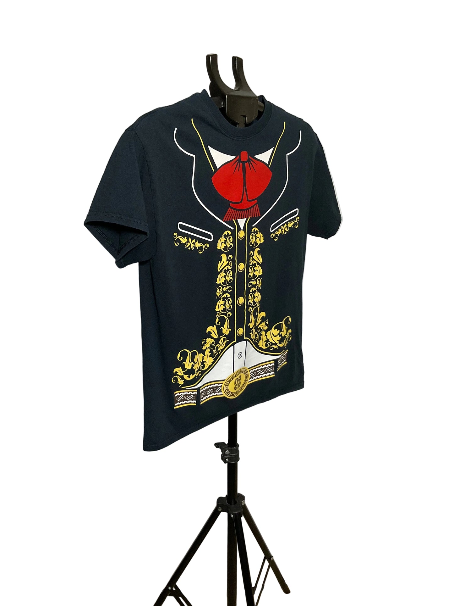 A navy blue short-sleeve t-shirt displayed on a black hanger stand against a white circular studio backdrop. The shirt features a large graphic print of a tuxedo jacket with gold baroque-style embroidery, a white shirt collar, and a red bow tie at the chest.