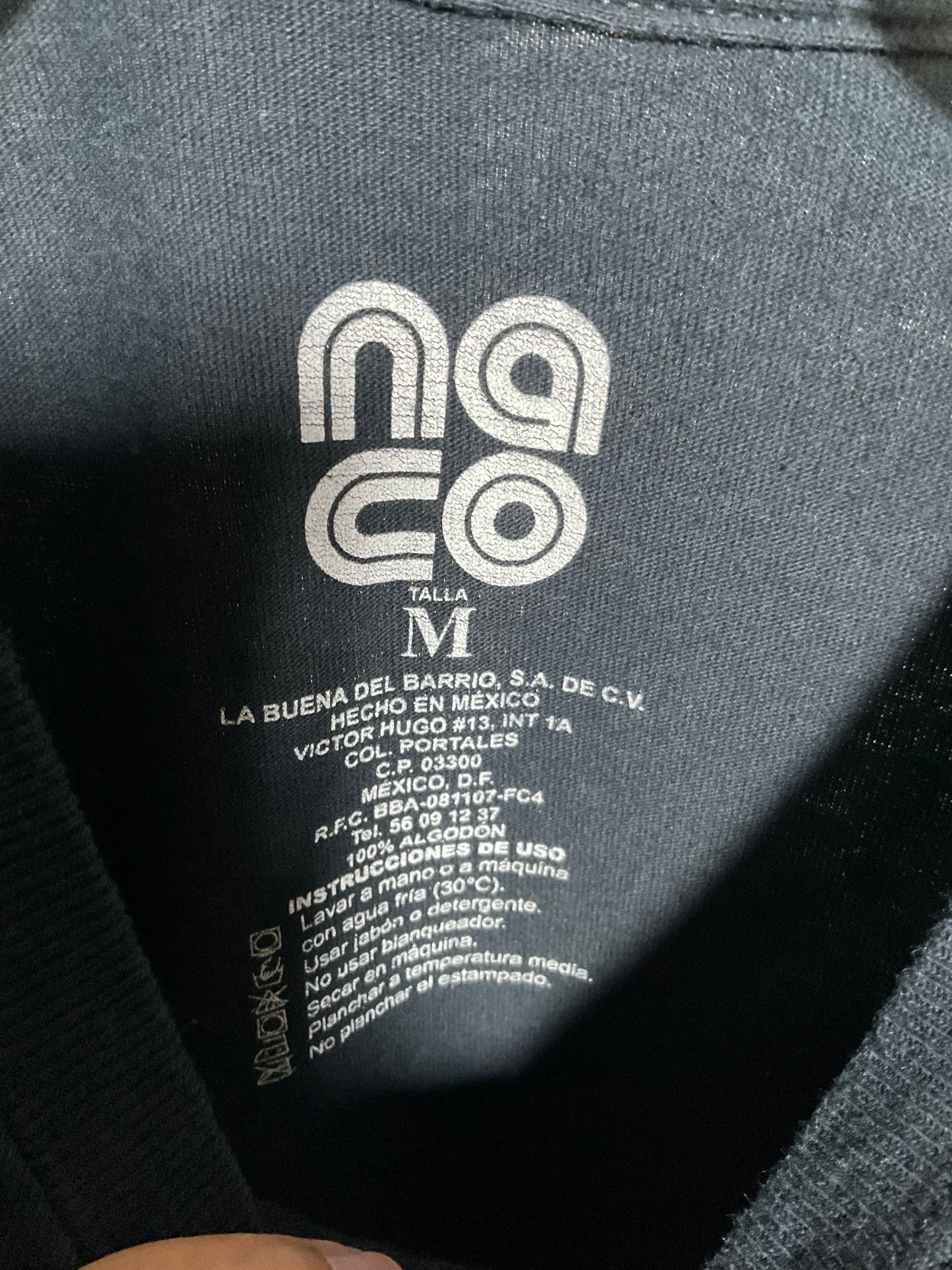 Close-up of the inside neck label of a dark gray garment, showing the white printed 'nacoco' brand logo and size information.