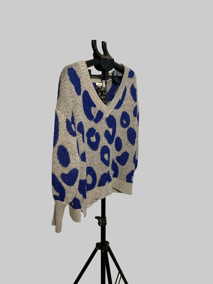 A gray and blue leopard-print knit sweater displayed on a black hanger stand in front of a white studio backdrop.