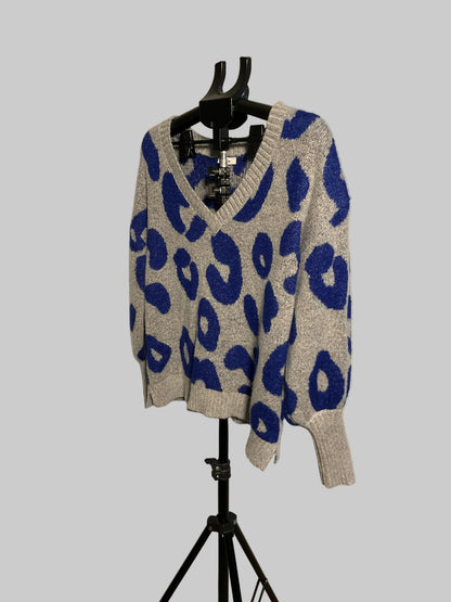 A knit V-neck sweater with a blue and gray leopard print pattern, displayed on a black hanger stand against a white studio backdrop.